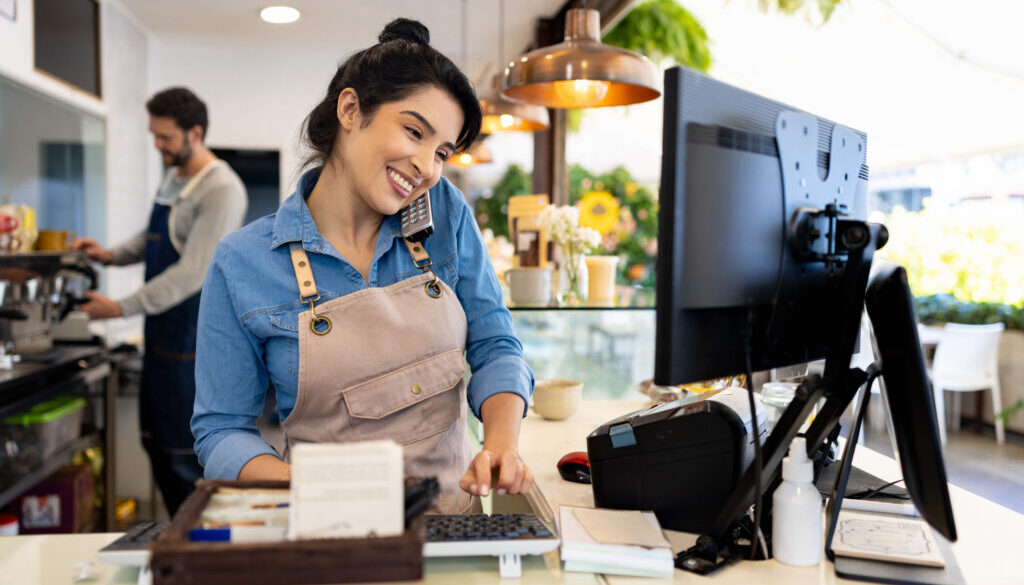 Happy waitress taking a delivery order on the phone at a coffee shop