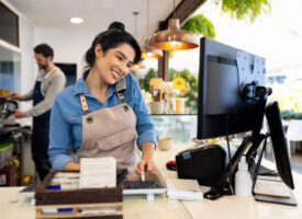 Happy waitress taking a delivery order on the phone at a coffee shop
