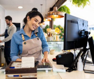 Happy waitress taking a delivery order on the phone at a coffee shop